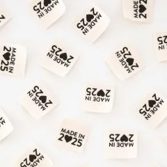 Nahaufnahme mehrerer „Made in 2025"-Endfalt-Weblabel dicht nebeneinander verstreut.