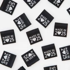 Nahaufnahme mehrerer „Made in 2025"-Weblabel dicht nebeneinander verstreut.