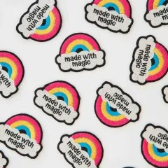 Nahaufnahme mehrerer Regenbogen-Patches „Made with Magic" dicht nebeneinander verstreut.