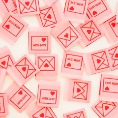 Dicht verstreute rosa Weblabels mit Umschlag-Vorderseite und "With Love"-Rückseite in Nahaufnahme.