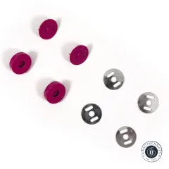 Nahaufnahme der pinkfarbenen Druckknopf-Hälften, bei denen die feinen Metallstifte auf der Rückseite deutlich zu erkennen sind, daneben vier gelochte Unterlegscheiben.