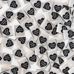 Viele Sarah Hearts Weblabels „Thanks I Made It" dicht verstreut in Nahaufnahme, teils mit sichtbarer Rückseite.