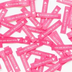 Viele pinke Sarah Hearts Weblabels „You are Beautiful" dicht überlappend verstreut, Nahaufnahme.
