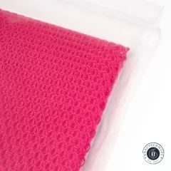 Weitere Nahaufnahme des gefalteten pinkfarbenen Netzstoffs mit Blick auf die Webstruktur.