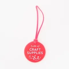 Neonpinker Sarah Hearts Gepäckanhänger „Full of Craft Supplies" aus Vinyl mit Näh-Symbol und Schlaufe.