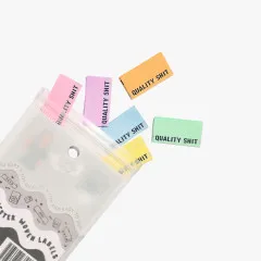 Pastellfarbene Quality-Shit-Labels teils aus der geöffneten Verpackung herausgezogen