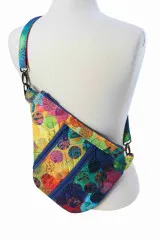 Rückansicht der Tasche am Modell in buntem Kreismuster-Stoff mit türkisfarbenem Trageriemen.