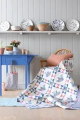 Patchwork-Quilt mit geometrischem Schwan-Muster aus der Summer-Kollektion, über einen Stuhl drapiert.