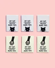 Drei Labels mit Katzengesicht und drei mit Pfotenabdruck-Motiv nebeneinander auf rosa Hintergrund.
