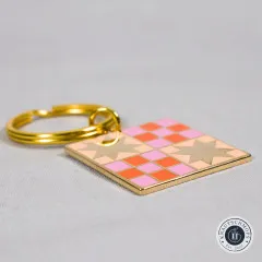 Quilt-Muster-Schlüsselanhänger seitlich liegend auf grauem Stoffuntergrund.