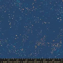 Nahaufnahme des Ruby Star Society Speckled Stoffs in Bluebell: dunkelblauer Fond mit lachsfarbenen und türkisen Farbsprenkeln, Marken-Maßband zeigt die Musterdichte.