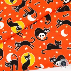 Gefalteter Halloweenstoff mit schwarzen Katzen, Fledermäusen und Monden auf orangem Grund in Nahaufnahme
