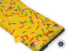 Der gelbe Konfetti-Tape-Stoff gefaltet und drapiert, mit sichtbarem Etikett am Stoffballen.