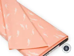 Der pfirsichfarbene Delfin-Stoff gefaltet und drapiert auf weißem Untergrund.