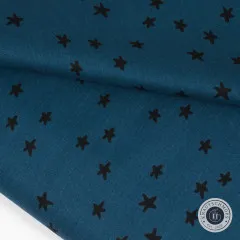 Der petrolblaue Sternen-Stoff gefaltet und drapiert, mit sichtbarem Barcode-Etikett am Stoffballen.