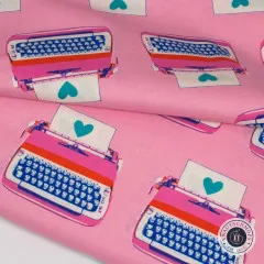 Nahaufnahme des gefalteten pinkfarbenen Stoffs mit Detailansicht der Schreibmaschinen und Herzchen.