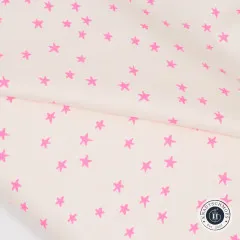 Nahaufnahme des gefalteten cremefarbenen Stoffs mit Detailansicht der pinkfarbenen Sterne.