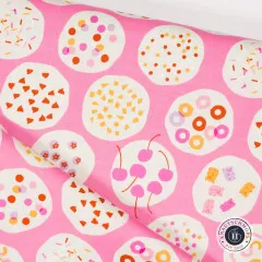 Diagonal gefalteter Stoff mit Detailansicht mehrerer Toppings-Kreise, darunter Kirschen und Gummibärchen.