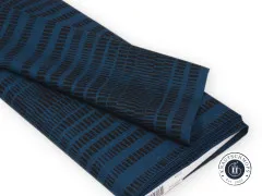 Zusammengelegter Stoffballen zeigt den Faltenwurf des High-Tide-Designs in Schwarz auf Petrolblau.