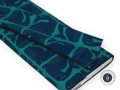 Zusammengelegter Stoffballen zeigt den Faltenwurf des Grumpy-Whale-Designs in Navy auf Petrol.