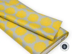 Zusammengelegter Stoffballen zeigt den Faltenwurf des Sunshine-Designs in Gelb auf Graublau.