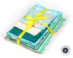 Nahaufnahme des mit gelbem Band gebundenen Fat-Quarter-Stoffpakets in Mint, Tuerkis und floralen Mustern