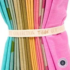 Nahaufnahme der gefalteten Stoffkanten in Türkis, Grün, Gelb und Pink mit dem Baumwollband „Tilda Quilt Collection".