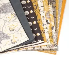 Detailansicht der gestapelten Quiltstoffe mit Mondphasen-, Blüten- und Farnmustern