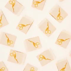 Weitere Nahaufnahme der Weblabels mit von Vintage-Stickscheren inspiriertem Storchenscheren-Aufdruck in Gold.