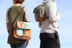 Zwei Personen im Freien tragen die Switchback-Tasche einmal als Umhängetasche und einmal als Rucksack in Batik-Stoffen.
