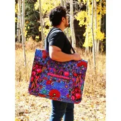 Eine Person trägt die große Portfolio-Tasche im Blumendesign über der Schulter im Freien.