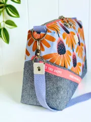 Seitliche Detailaufnahme der Umhängetasche mit Denim-Stoff, Trageriemen und Metallbeschlägen.