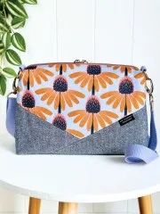Fertige Umhängetasche mit Denim-Unterteil und geblümtem Oberteil, dekorativ auf einem Tisch drapiert.