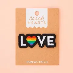 Verpackungskarte des Love-Pride-Patches flach liegend fotografiert, ohne Hand im Bild.