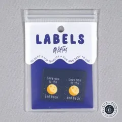 Verpackungskarte „Labels by KATM" mit zwei sichtbaren „Love You To The Moon and Back"-Labels, gerade von vorne fotografiert.