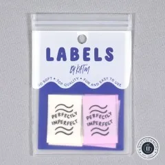 Verpackungskarte „Labels by KATM" mit den „Perfectly Imperfect"-Labels in Elfenbein und Flieder, gerade von vorne fotografiert.