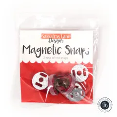 Frontale Ansicht der Verpackung mit Markenlogo, Produktname „Magnetic Snaps" und dem Hinweis „2 sets of red snaps".