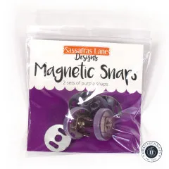 Frontale Ansicht der Verpackung mit Markenlogo, Produktname „Magnetic Snaps" und dem Hinweis „2 sets of purple snaps".