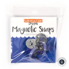 Frontale Ansicht der Verpackung mit Markenlogo, Produktname „Magnetic Snaps" und dem Hinweis „2 sets of royal blue snaps".