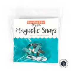 Frontale Ansicht der Verpackung mit Markenlogo, Produktname „Magnetic Snaps" und dem Hinweis „2 sets of iridescent snaps".