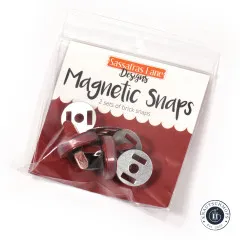 Originalverpackung der Sassafras Lane Magnetic Snaps in Brick, schräg fotografiert mit sichtbaren Druckknöpfen und Scheiben im Beutel.