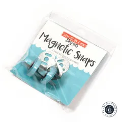 Originalverpackung der Sassafras Lane Magnetic Snaps in Light Blue, schräg fotografiert mit sichtbaren Druckknöpfen und Scheiben im Beutel.