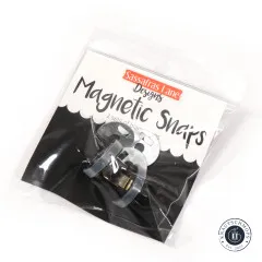 Schräg fotografierte Verpackung 'Magnetic Snaps' von Sassafras Lane Designs mit zwei Sets schwarzer Magnet-Druckknöpfe im Beutel.