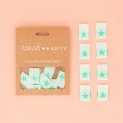 Sarah-Hearts-Verpackung „Star" in Mint, daneben alle acht Weblabel aus weichem Polyester.