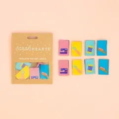 Sarah-Hearts-Weblabel „Sewing Tools" in Kraftpapier-Verpackung neben allen acht Labels mit Nähmaschine, Rollschneider, Fadenspule und Maßband in Rosa, Gelb, Mint und Blau.
