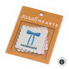 Sarah Hearts Weblabel „Bows Handmade“ mit blauer Schleife, sichtbar durch das Fenster der Verpackung.