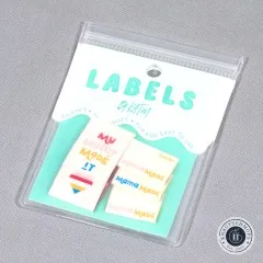 Verpackte Kylie and The Machine Label-Sets „My Mama Made It" und „Mama Made" mit Herz-Symbol auf türkisfarbener Verpackungskarte.