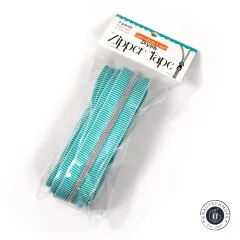 Schräg aufgenommene Originalverpackung 'Zipper Tape' von Sassafras Lane Designs mit aufgerolltem Teal-Stripe-Band im Beutel.