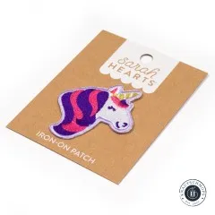 Verpackungskarte des Einhorn-Aufnähers schräg fotografiert, mit Knautschmops-Logo im Bild.