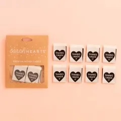 Sarah Hearts Verpackungskarton mit 8 grauen Weblabels, schwarzes Herz mit Schriftzug „Thanks I Made It" auf rosa Hintergrund.